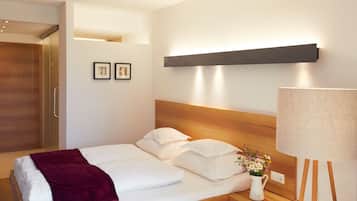 A hotel room with a bed, a nightstand with a lamp, a wooden headboard, and a wardrobe.