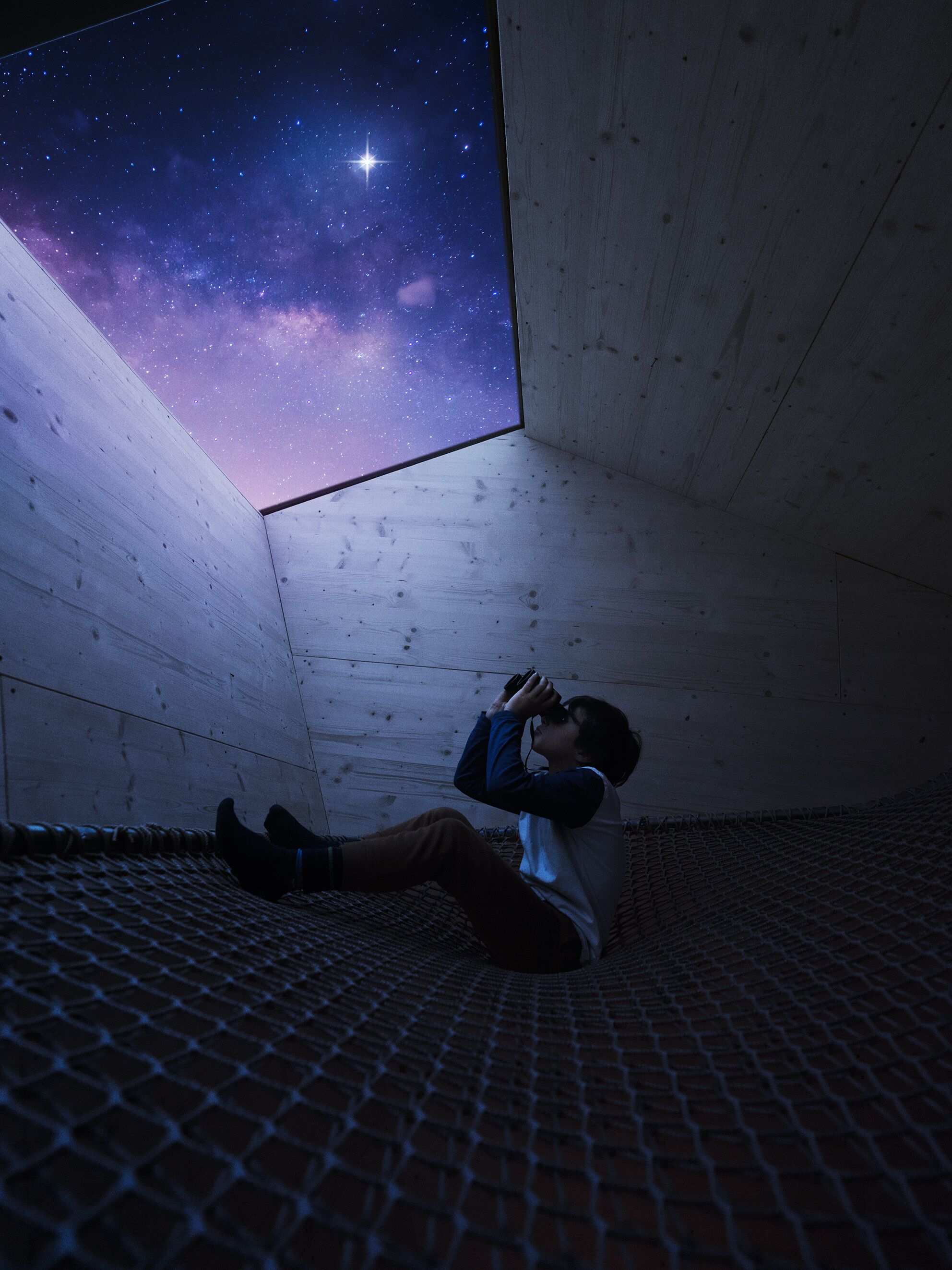 A person lying on a brick floor in a room with a large window displaying a starry night sky.