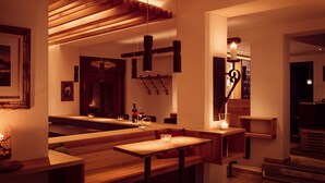 A modern interior with wooden benches and tables, pendant lighting, and a staircase leading to another level. - Der Stern - Wirtshaus und Landhotel für Generationen seit 1509 (Obsteig)