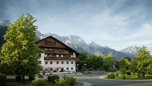 A hotel with a wooden facade, outdoor seating, and a view of snow-capped mountains. - Der Stern - Wirtshaus und Landhotel für Generationen seit 1509 (Obsteig)