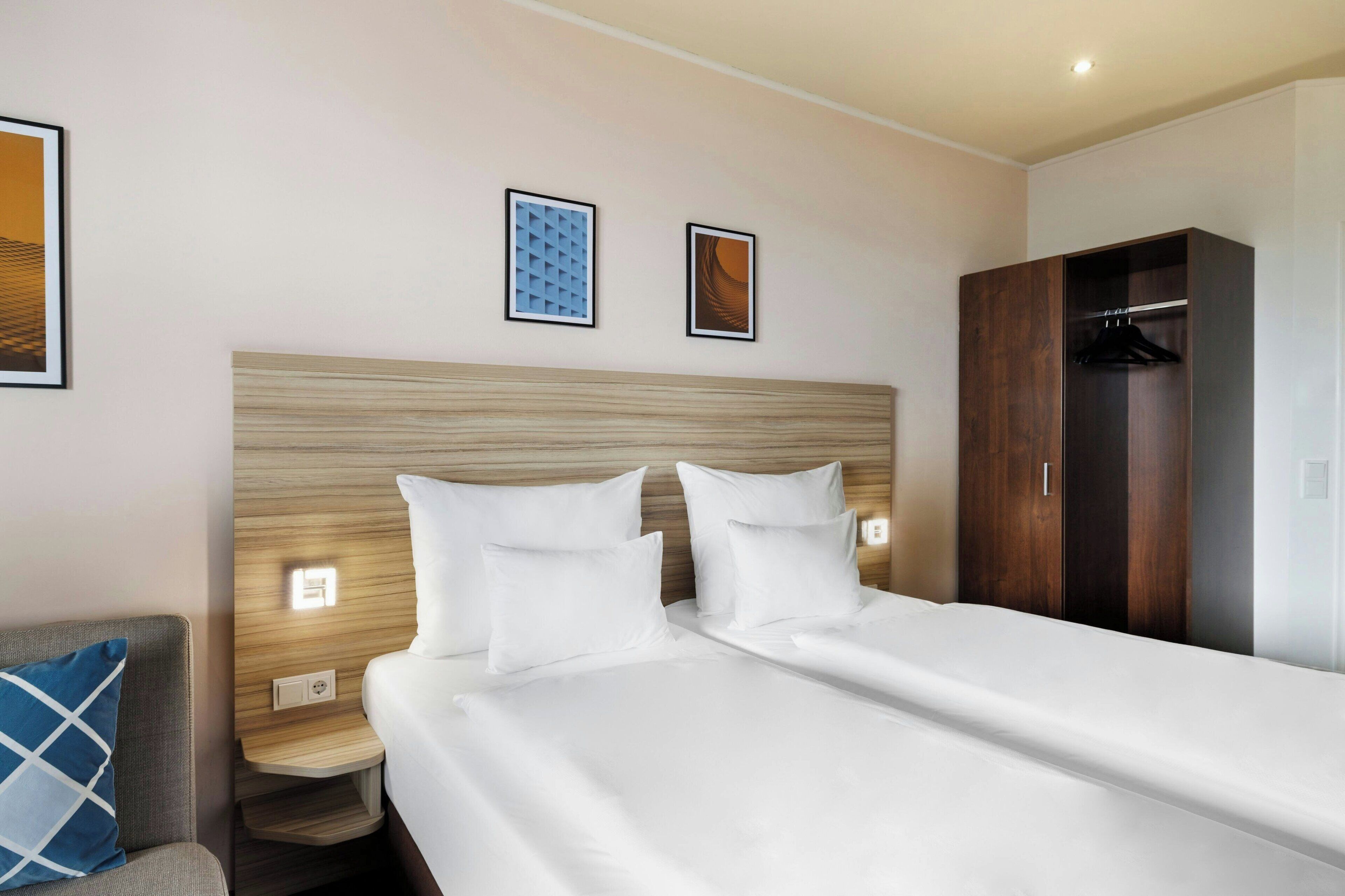 Ein Hotelzimmer mit einem großen Bett, einem hölzernen Kopfteil, einem Kleiderschrank und zwei Wandleuchten.