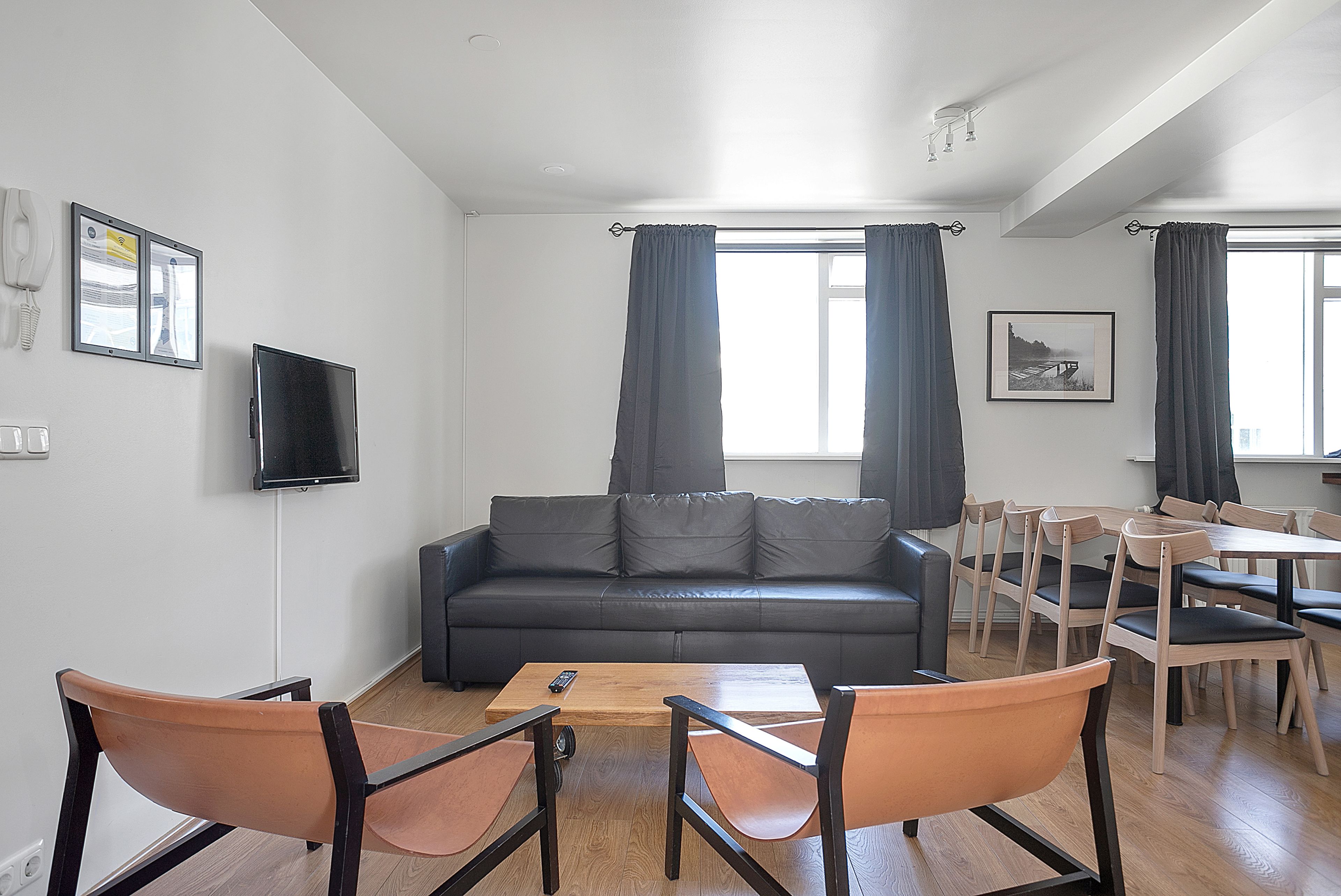A living room with a sofa, two chairs, a coffee table, a TV, and a dining area with chairs and a table.
