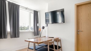 A room with a wooden table, two chairs, a TV mounted on the wall, and a door. - Stay Apartments Einholt (Reykjavik)