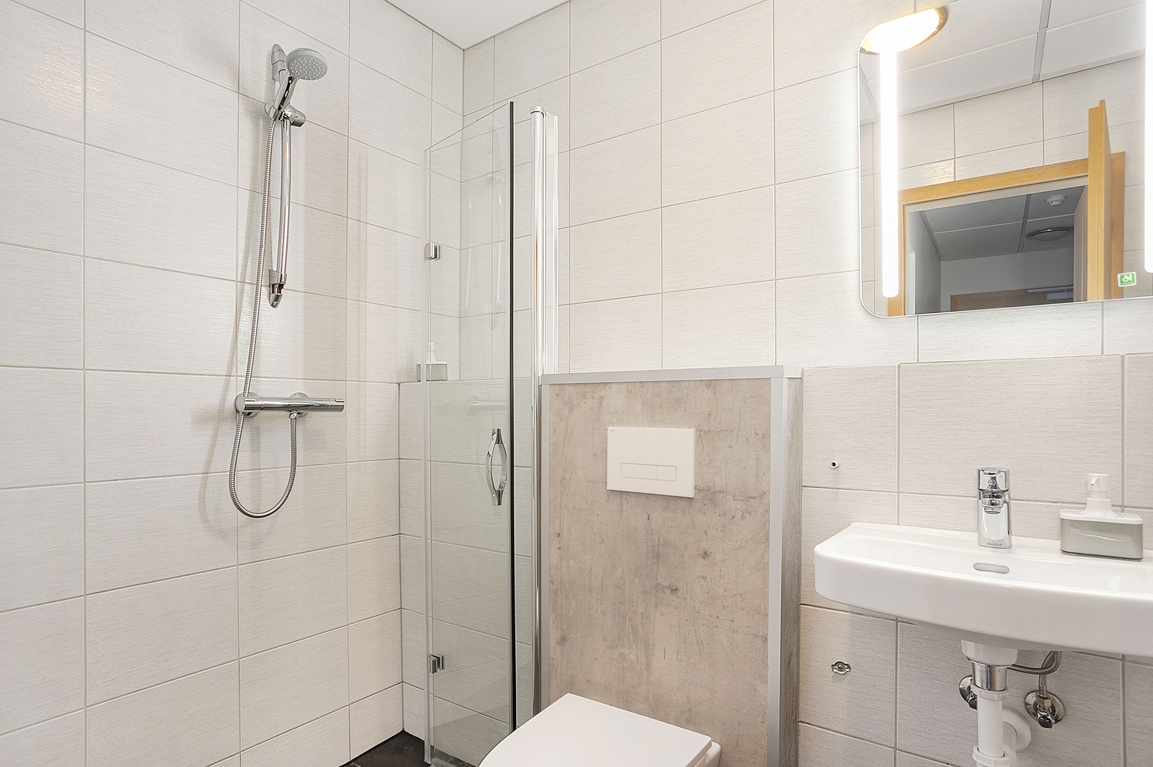 A modern bathroom with a glass-enclosed shower, a white sink, and a mirror with a wooden frame.