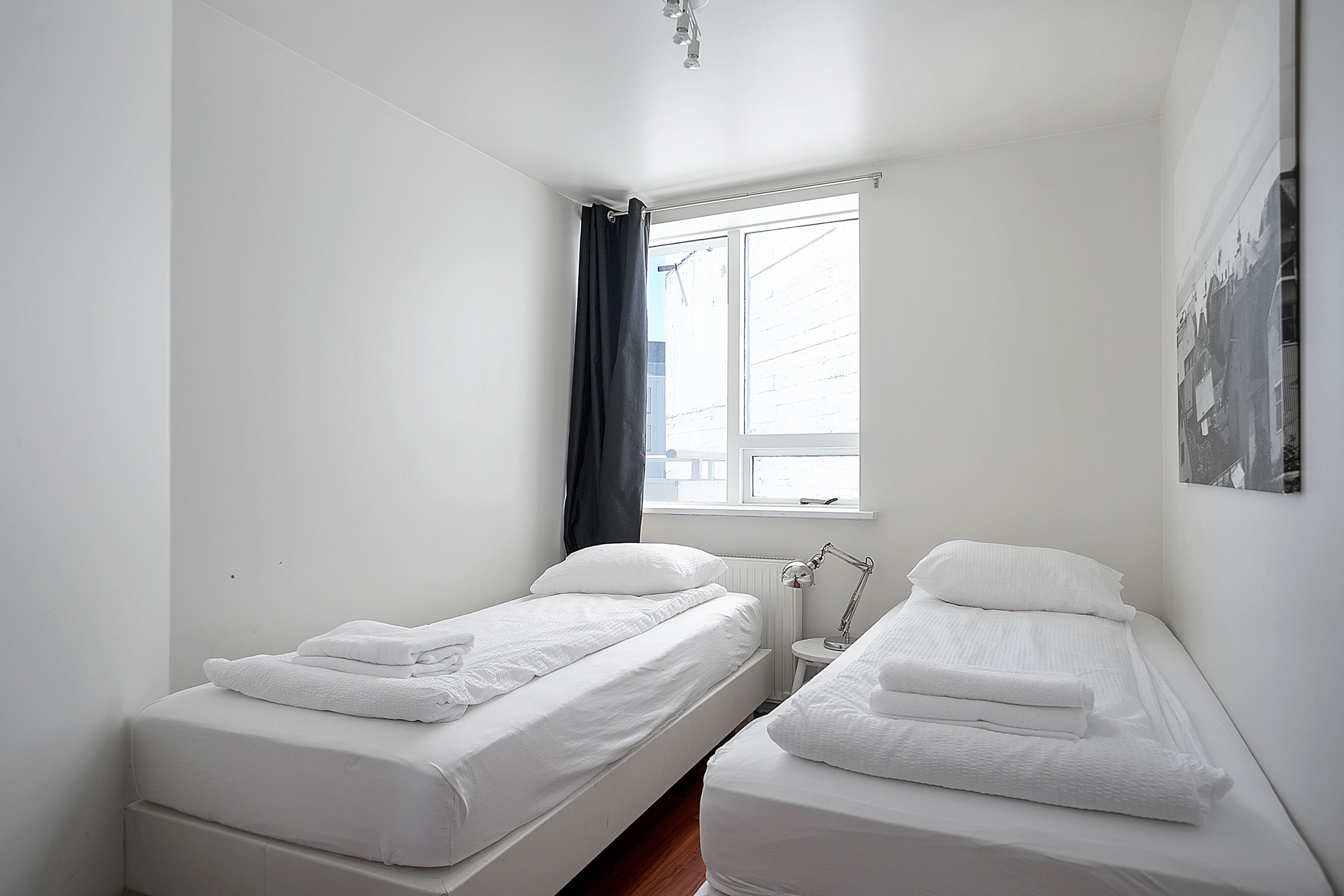 A small, clean room with two beds, a window, and a radiator.