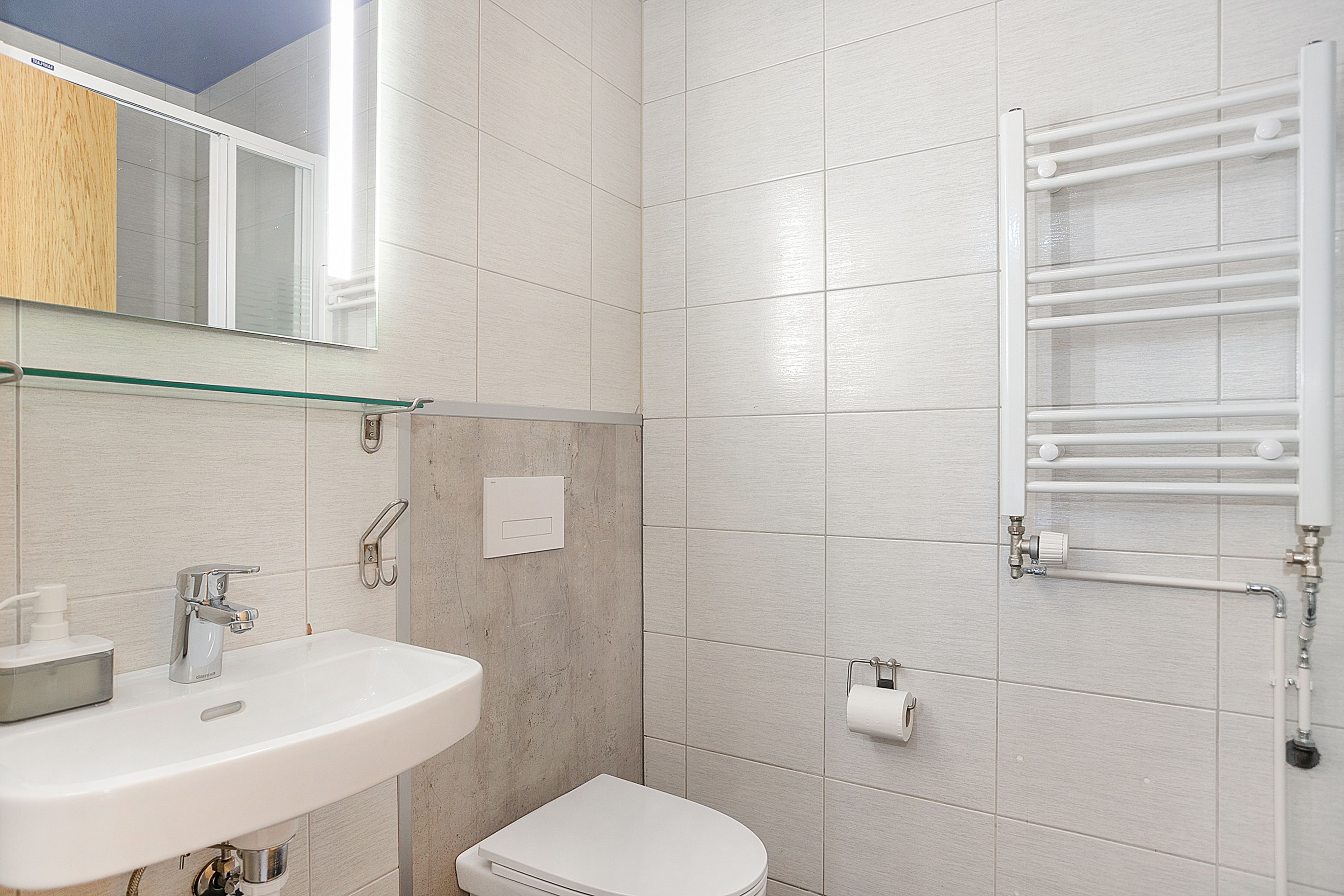 Ein Badezimmer mit weißem Waschbecken, Toilette und Ablage über dem Waschbecken.