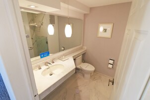 Un baño con un espejo grande, un lavabo, inodoro y ducha.