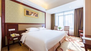 Una habitación de hotel con una cama grande, un escritorio con teléfono y una silla.