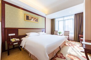 A hotel room with a large bed, a desk with a telephone, and a chair. - Vienna Hotel Guangzhou Shaheding Metro Station Branch (Guangzhou)