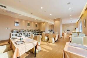 Un espace repas comprenant plusieurs tables et chaises, des buffets et des œuvres d’art accrochées aux murs.