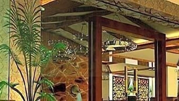 Un vestíbulo amplio con techos altos, ventanas grandes y plantas tropicales.