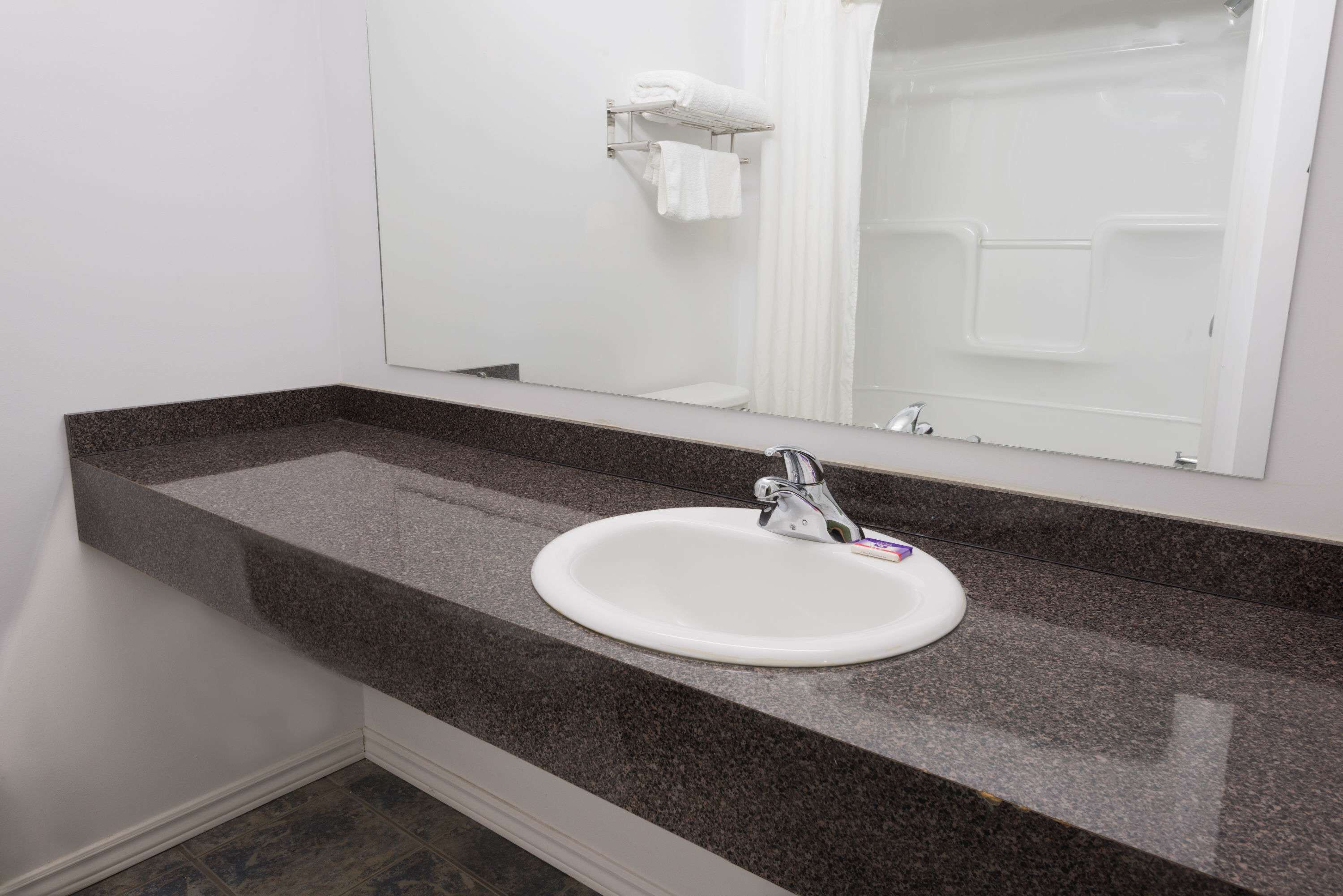 A bathroom with a white sink, granite countertop, and a mirror above the sink.