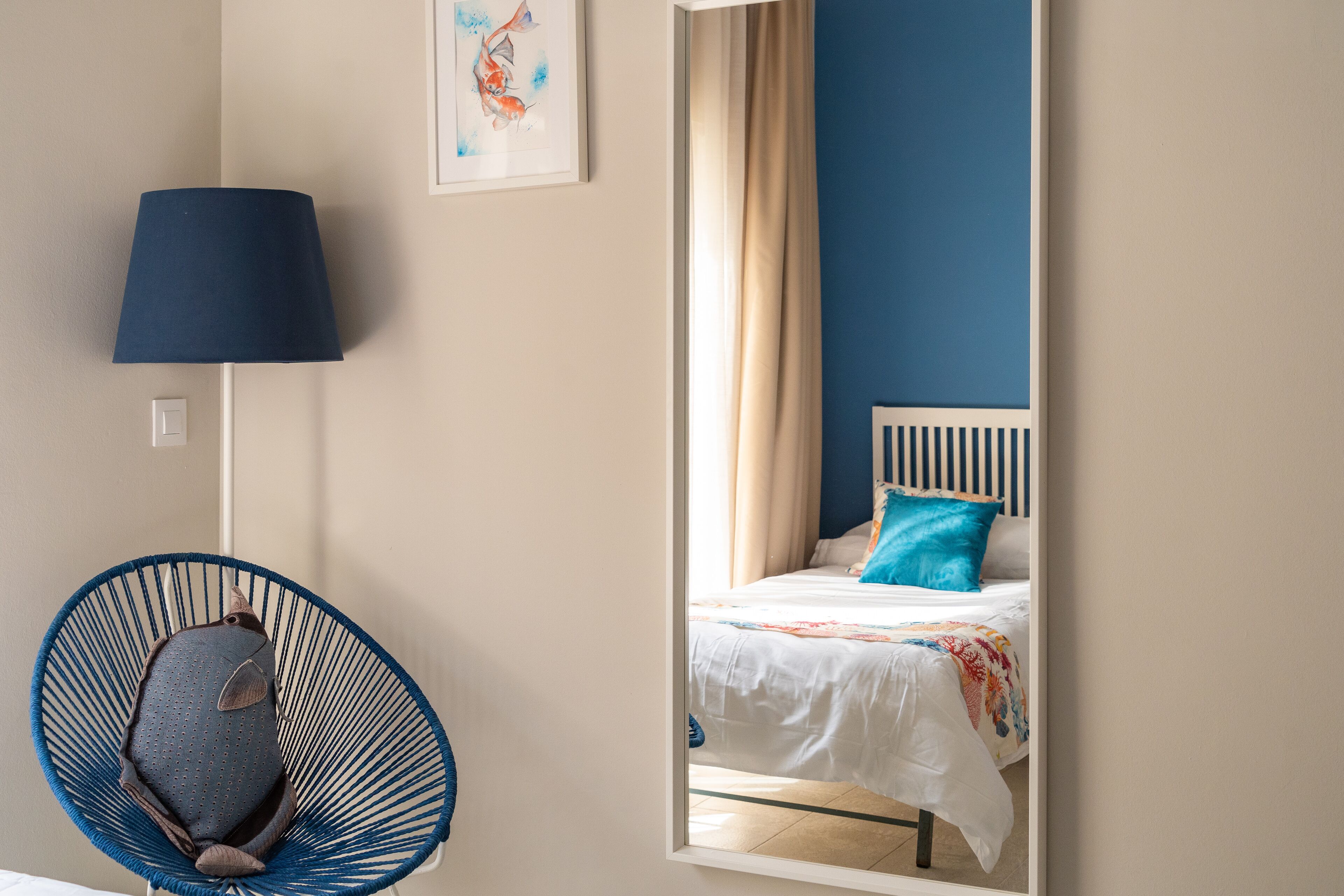 Quarto com cama, poltrona, abajur e um quadro na parede.