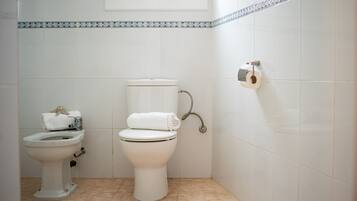 A bathroom with a toilet, bidet, and a towel rack.