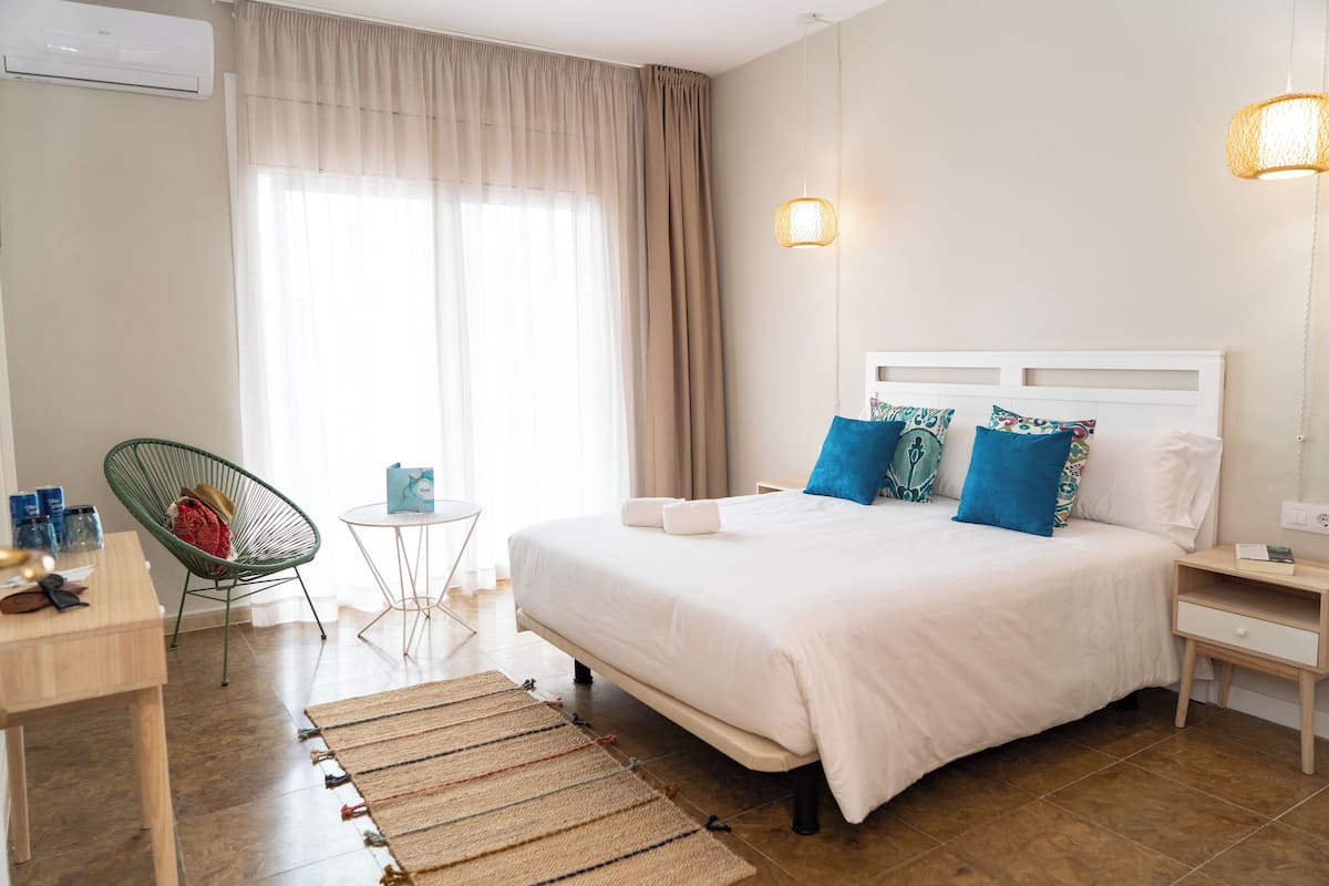 Une chambre d’hôtel avec un grand lit, une chaise, une petite table et une lampe de chevet.