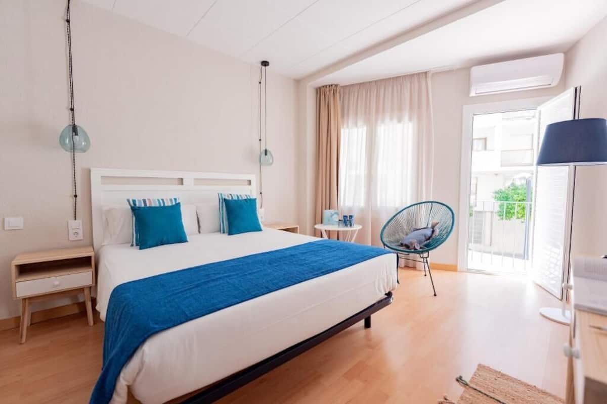 Une chambre d’hôtel moderne avec un grand lit, une petite table, une chaise et une vue sur l’extérieur.