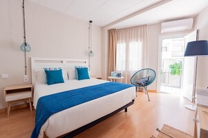 Habitación de hotel moderna con una cama grande, una mesita pequeña, una silla y vistas al exterior.
