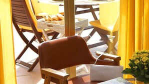 A balcony with yellow chairs, a round table, and a glass table with a book. - Bulevard Hotel (Castell-Platja d'Aro)