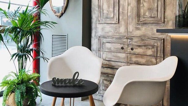 A modern interior with a round table, two white chairs, a mirror, and a large wooden door. - Bulevard Hotel (Castell-Platja d'Aro)