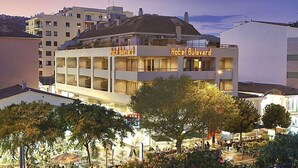 A hotel with multiple floors, balconies, and a central courtyard with trees and outdoor seating. - Bulevard Hotel (Castell-Platja d'Aro)