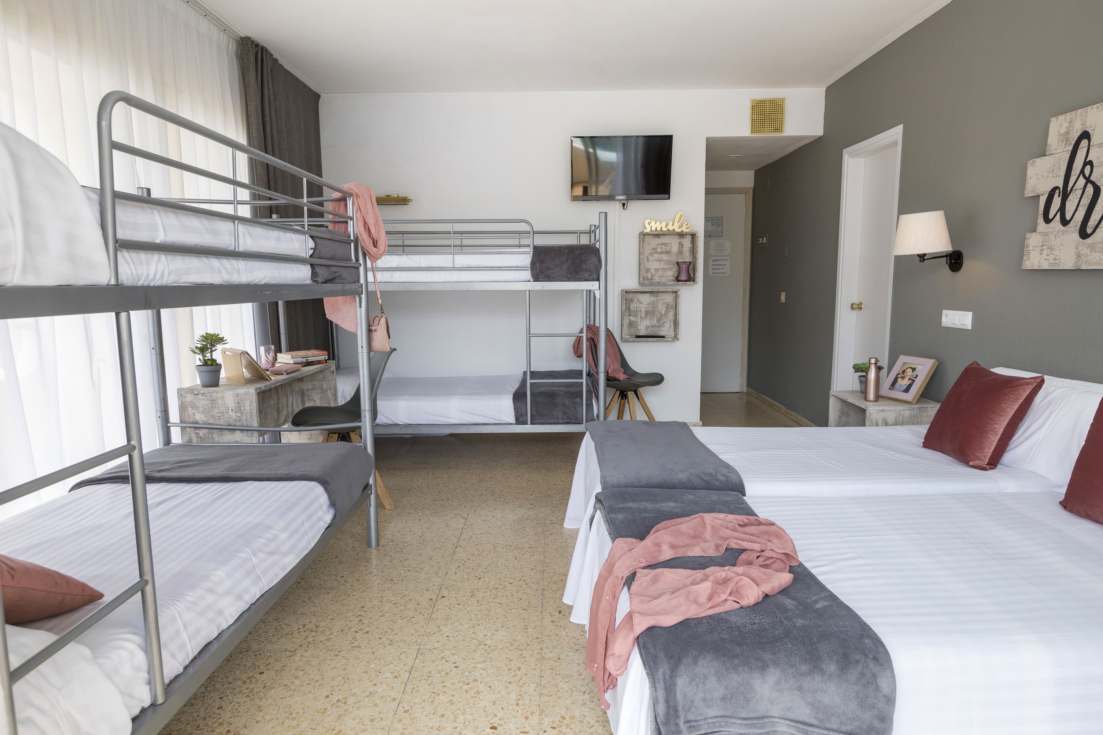 Una habitación de hotel con literas, televisión, escritorio y cama con almohada.