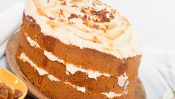 A layered cake with frosting on a wooden board.