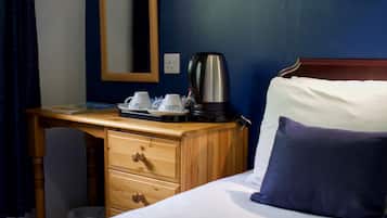 Una habitación de hotel con una cama, un escritorio de madera, una cafetera y una bandeja con tazas.