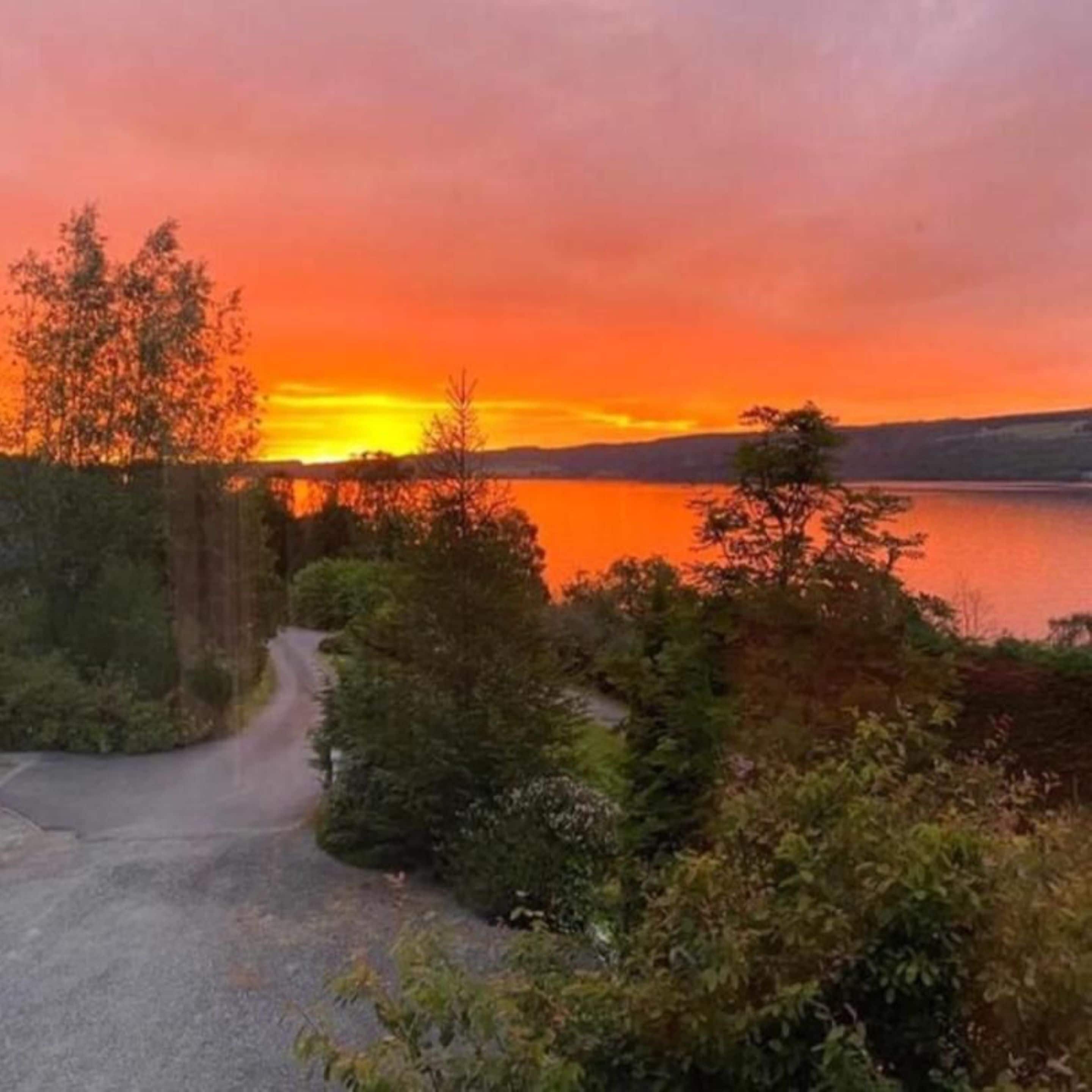 Vista panorámica de un lago al atardecer, con una carretera que conduce a un edificio.