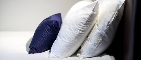 A bed with white and blue pillows.