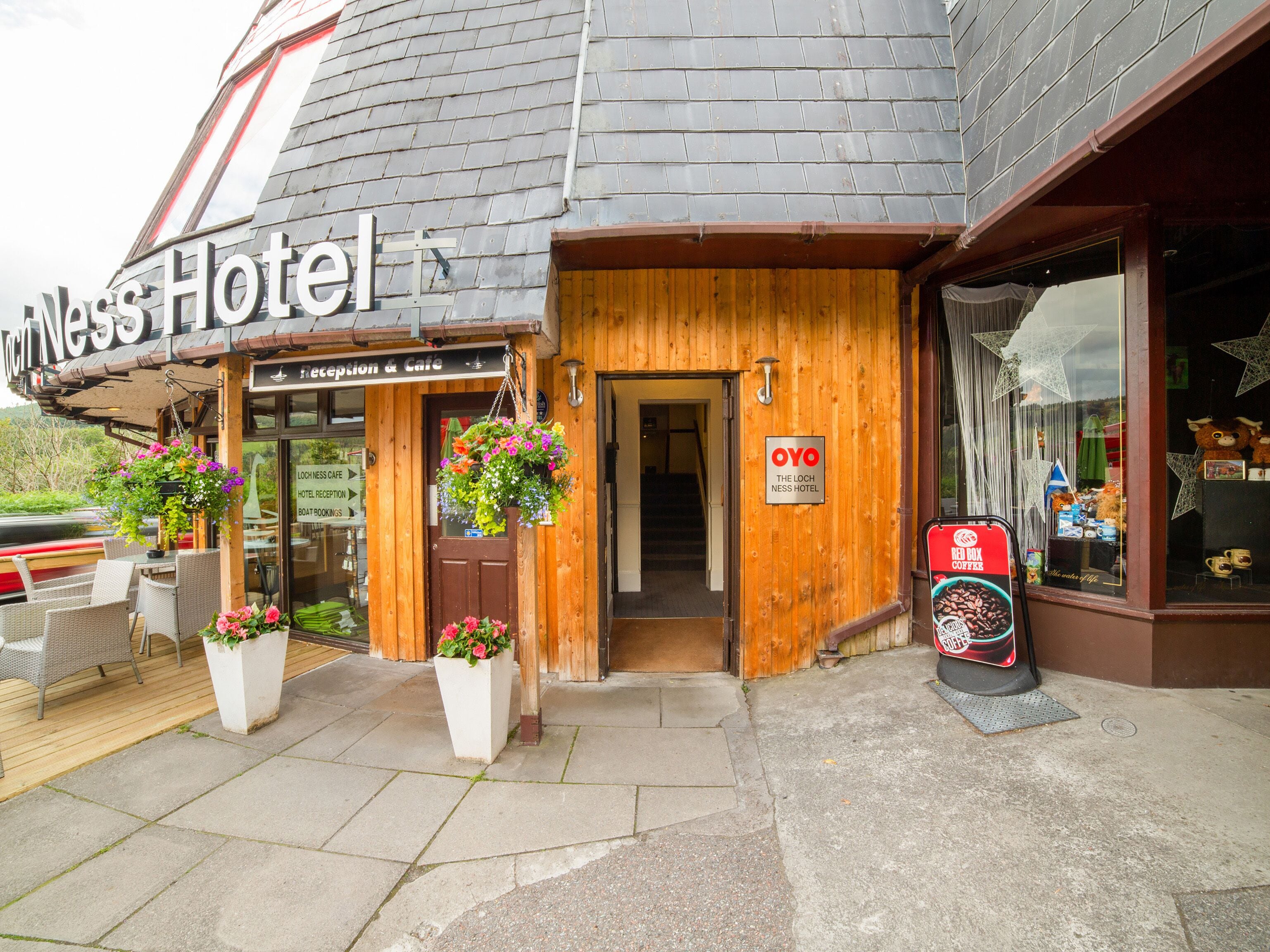 Hotel Loch Ness con una zona de recepción, asientos exteriores y un letrero que indica el nombre del hotel.