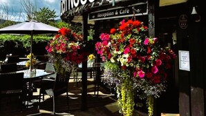 A building with a sign reading "Ness Reception & Cafe" and outdoor seating with tables and chairs.