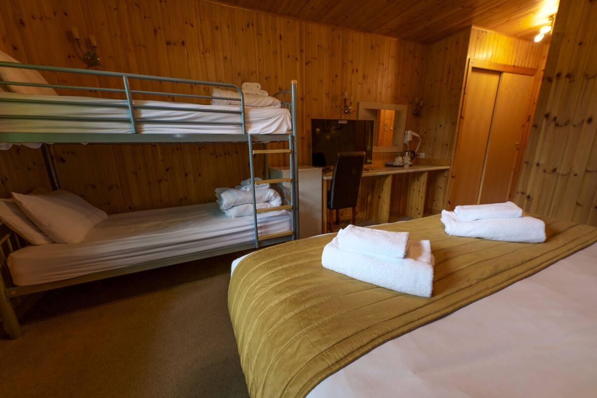 Ein Zimmer mit Etagenbetten, einem Schreibtisch und einem Bett mit Handtüchern.