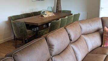 A modern living room with a brown leather sofa, a dining table with chairs, and two animal-themed wall art pieces.