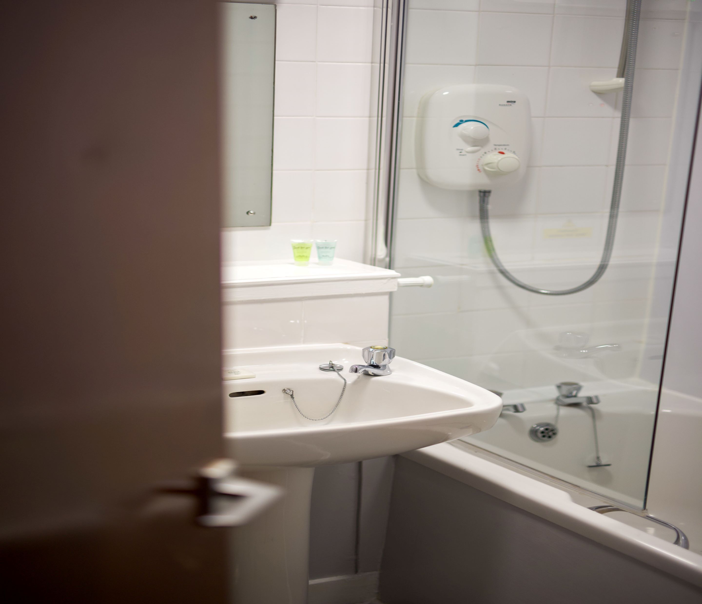 A bathroom with a white sink, a glass shower enclosure, and a toilet.