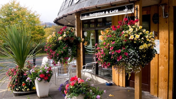 A hotel with a reception area, outdoor seating, and hanging flower baskets.