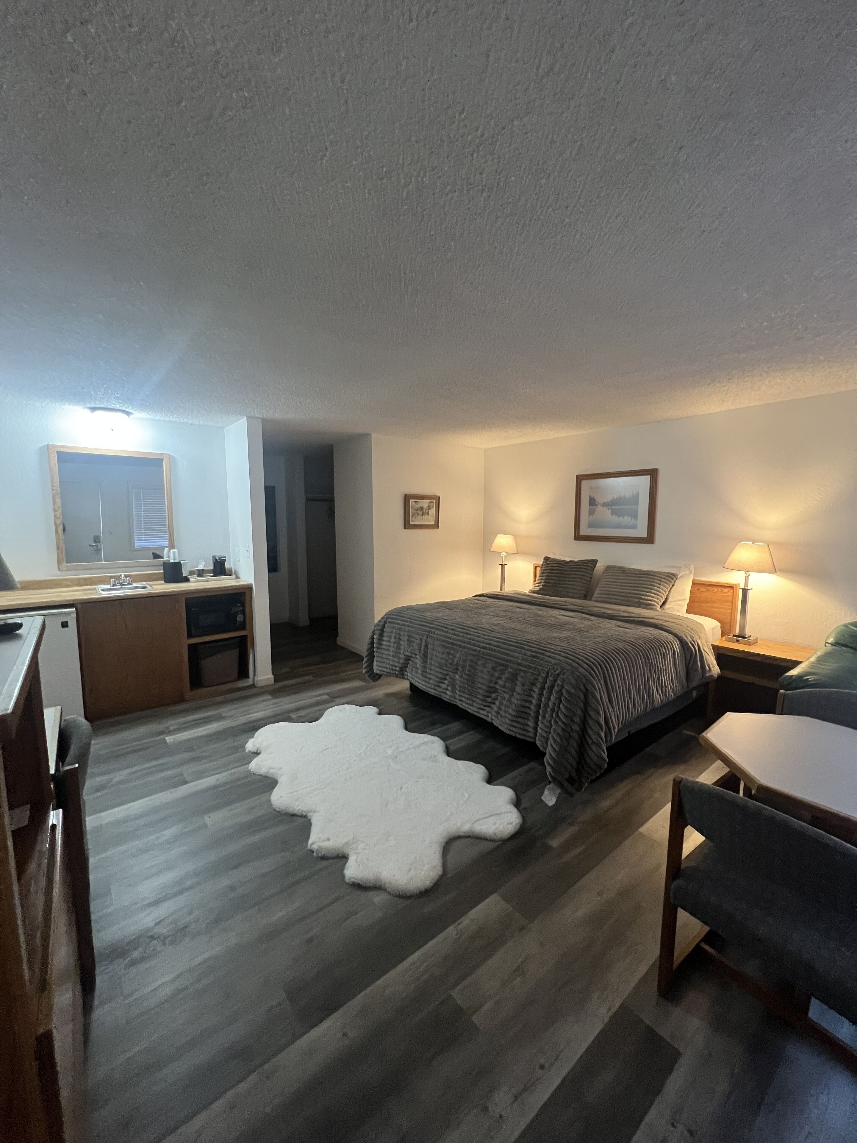 A bedroom with a bed, bedside tables, a desk, and a chair.