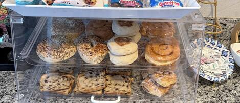 A display case with various muffins and donuts, including chocolate chip and frosted varieties.