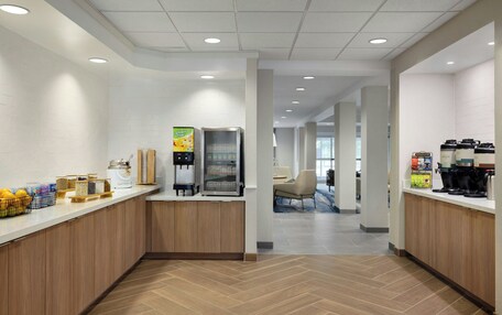 A modern kitchen area with a coffee machine, a refrigerator, and various food items on the counter.