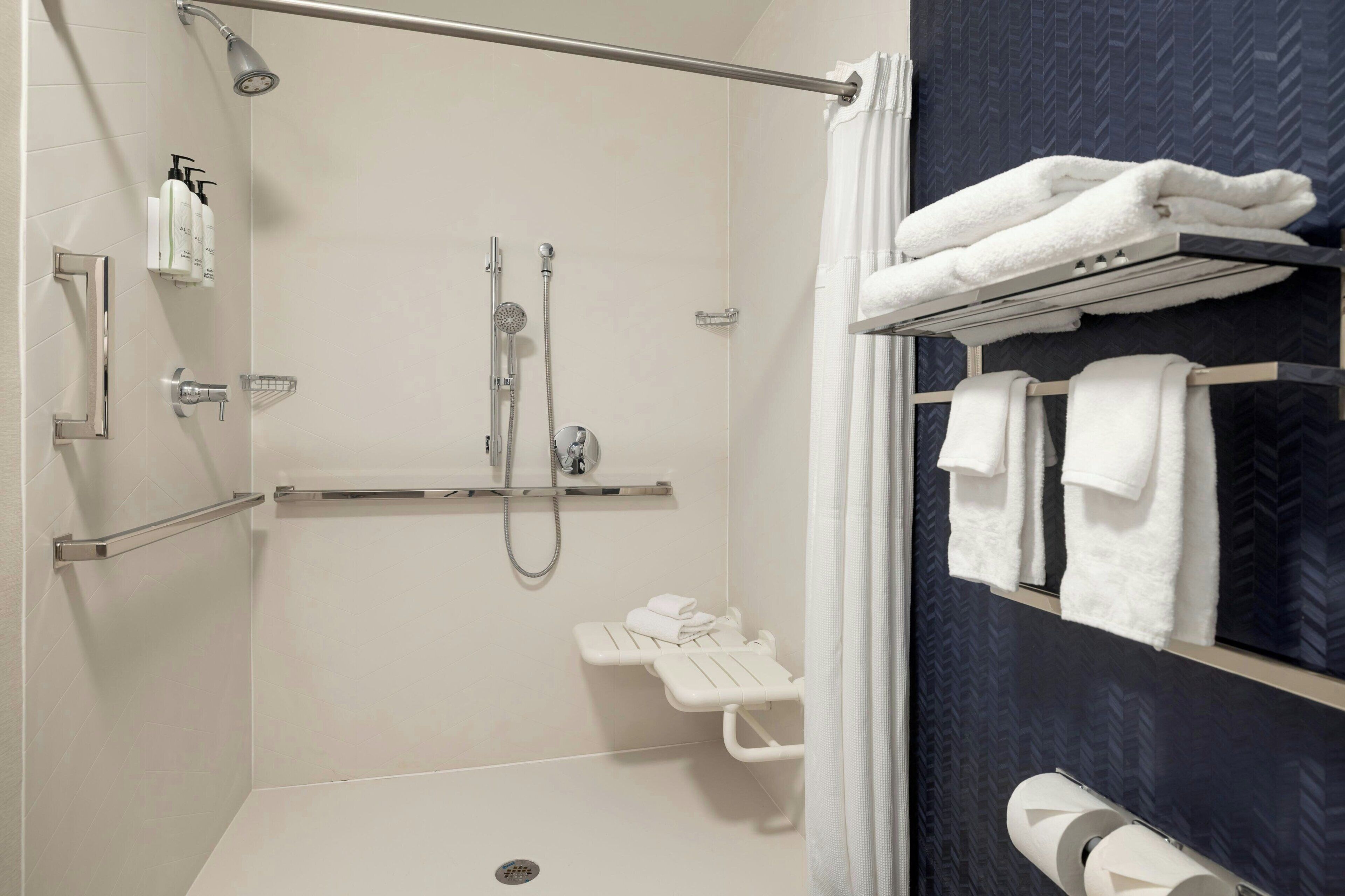 A modern bathroom with a shower, a towel rack, and a toilet paper holder.