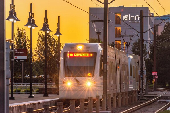 A train at a station with a sign for 'City Center' and a building labeled 'Aloft W Hotels'.