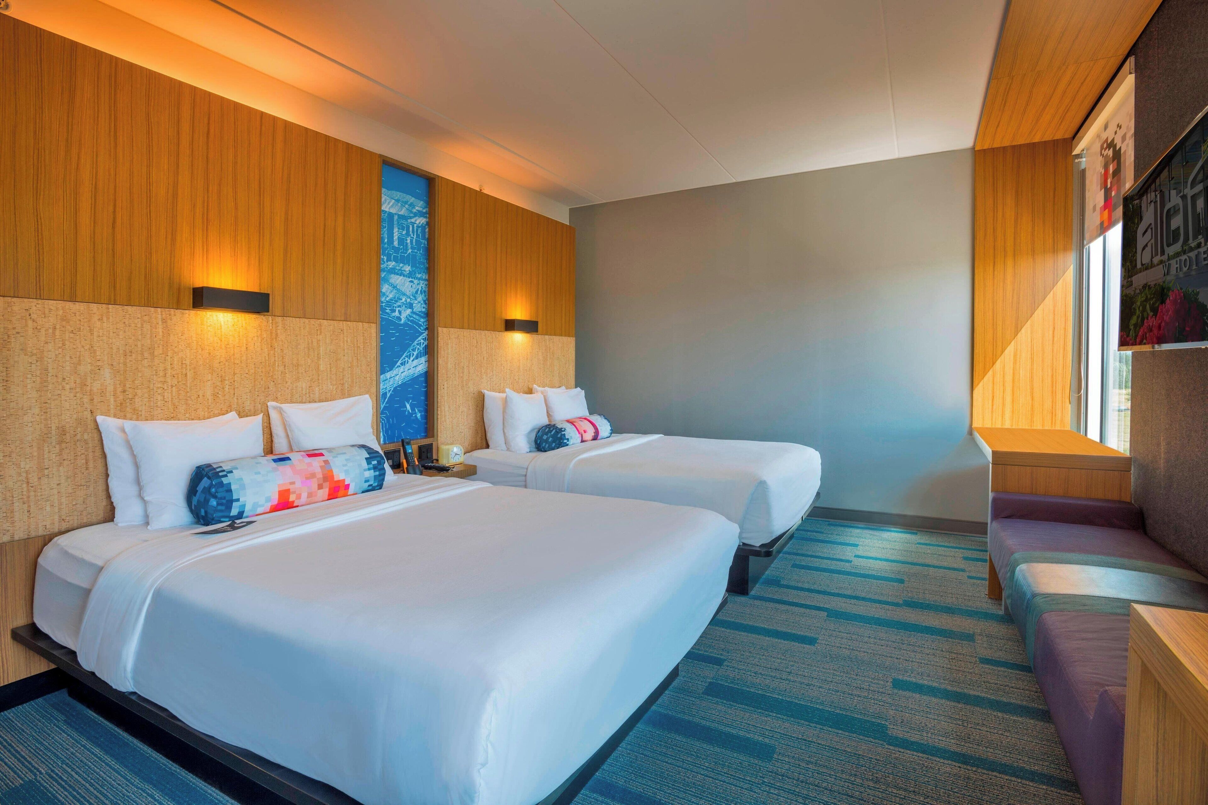 Une chambre d’hôtel avec deux lits, un canapé et une grande fenêtre.