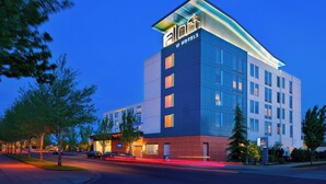 A modern hotel with a prominent 'aloft' sign, multiple floors, and a well-lit facade.