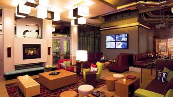 A modern lounge area with a fireplace, multiple seating options, and a large screen displaying a cityscape.