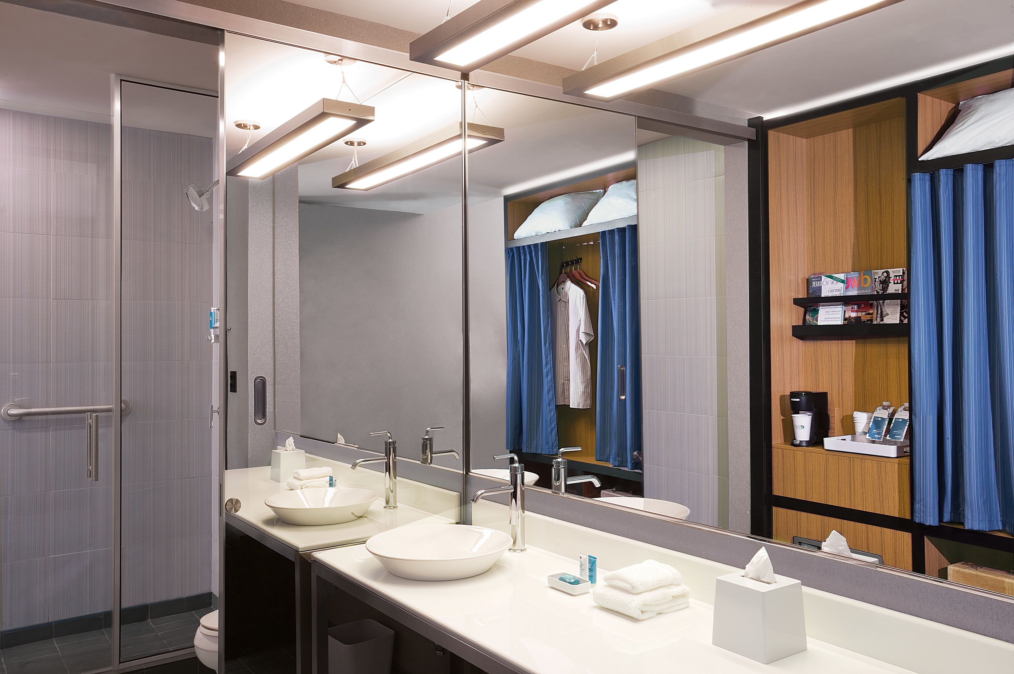 Un baño moderno con un espejo grande, dos lavamanos y una ducha.
