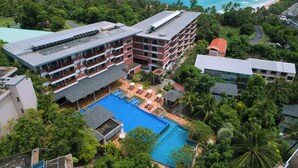 A hotel with multiple floors, a swimming pool, and lush greenery surrounding the property. - Peach Blossom Resort (Karon)