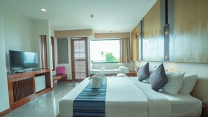 A hotel room with a bed, a TV, a small desk, and a window with a view. - Peach Blossom Resort (Karon)