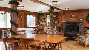 A wooden interior with a fireplace, bookshelves, and a dining area. - Dexter's Inn (Sunapee)