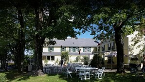 A courtyard with outdoor seating, surrounded by trees and a building with multiple windows. - Dexter's Inn (Sunapee)