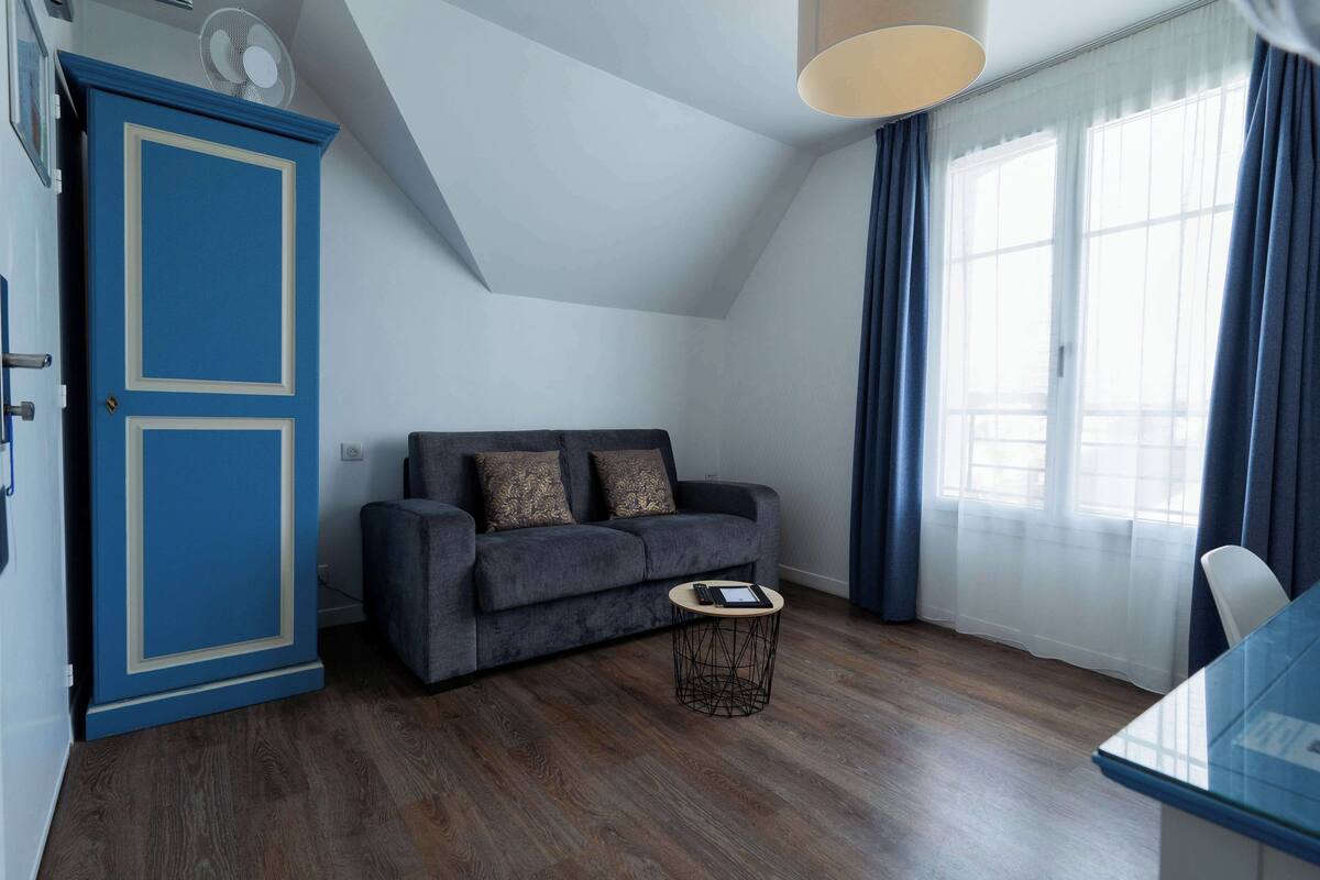 A modern living room with a dark grey sofa, a small round coffee table, and a blue cabinet.