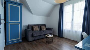 Een moderne woonkamer met een donkergrijze bank, een klein rond bijzettafeltje en een blauwe kast.